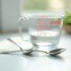 Cuillère en métal remplie d'eau sur plan de cuisine lumineux